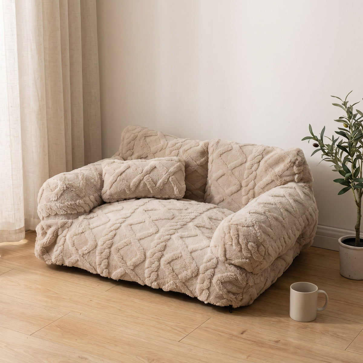 Beige plush sofa-style pet bed on a light oak floor